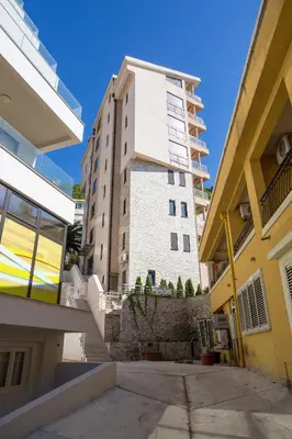 a tall building in the middle of two buildings at Apartments Lumiere in Rafailovici
