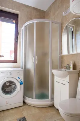 a bathroom with a shower and a washing machine at Apartments Lumiere in Rafailovici