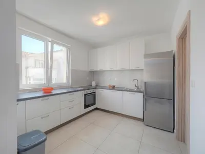 a kitchen with white cabinets and a stainless steel refrigerator at Family Three bedroom Apartment Brando in Budva