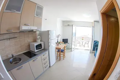 a kitchen with a refrigerator and a table with chairs at Apartments Charme in Becici