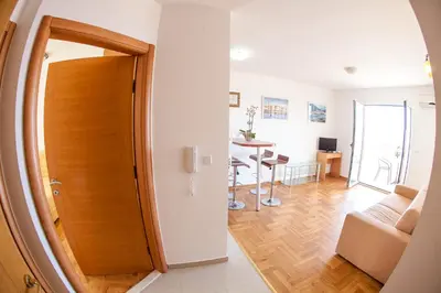 a room with a door and a living room with a table at Apartments Charme in Becici