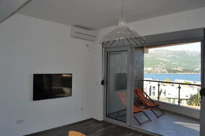 a room with a balcony with a tv and a chair at Old Town View Apartment in Budva