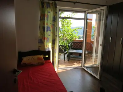 a bedroom with a bed and a sliding glass door at Apartments Victoriya in Sutomore