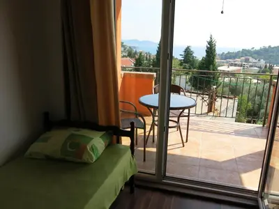 a bedroom with a bed and a balcony with a table at Apartments Victoriya in Sutomore