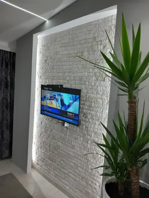 a wall mounted tv on a brick wall at Apartments Doha in Ulcinj