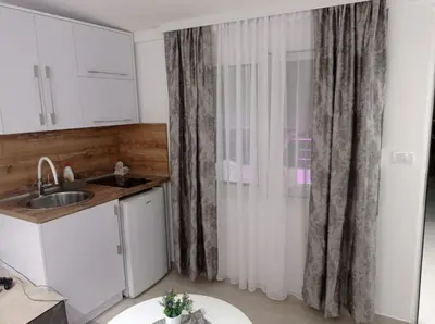 a kitchen with a sink and a window with curtains at Apartments Doha in Ulcinj