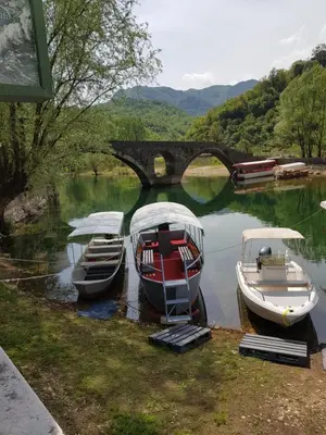 three boats are docked in the water near a bridge at Apartman Jovicevic Pavle in Rijeka Crnojevića