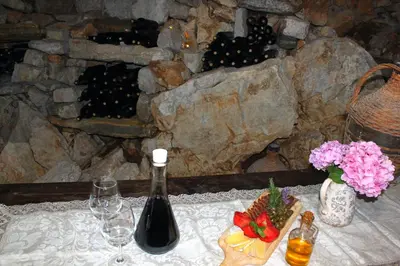 a table with a bottle of wine and a basket of grapes at Blue Mediterranean Apartments in Sveti Stefan