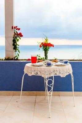 a table with plates and a vase with flowers on it at Blue Mediterranean Apartments in Sveti Stefan