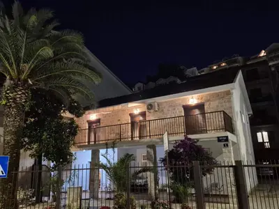 a building with a palm tree in front of it at Studio Apartments 6 Palmi in Budva