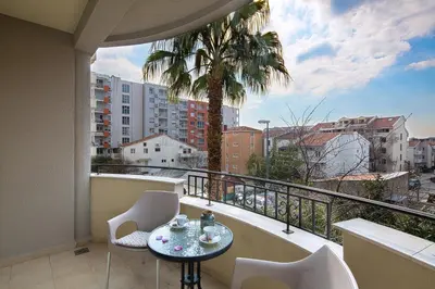 a balcony with a table and chairs and a palm tree at Le Marc Guest house in Budva