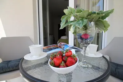 a glass table with a bowl of strawberries and a vase at Le Marc Guest house in Budva