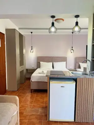 a bedroom with a bed and a kitchen with a counter at Apartments Fat e Jet - Pool & Breakfast in Ulcinj