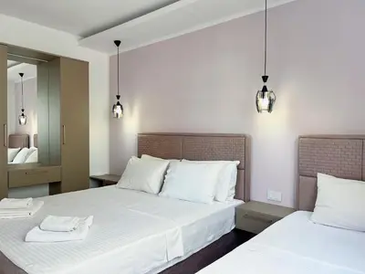 a bedroom with two beds with white sheets and two lights at Apartments Fat e Jet - Pool & Breakfast in Ulcinj