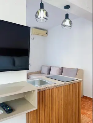 a living room with a flat screen tv and a counter at Apartments Fat e Jet - Pool & Breakfast in Ulcinj