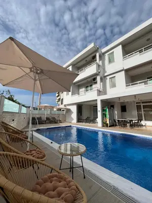 a pool with chairs and an umbrella next to a building at Apartments Fat e Jet - Pool & Breakfast in Ulcinj