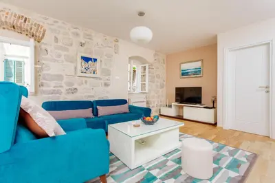 a living room with a blue couch and a tv at Old Town Museum Square Apartment in Kotor