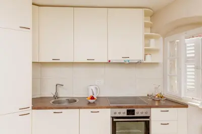 a kitchen with white cabinets and a sink at Old Town Museum Square Apartment in Kotor