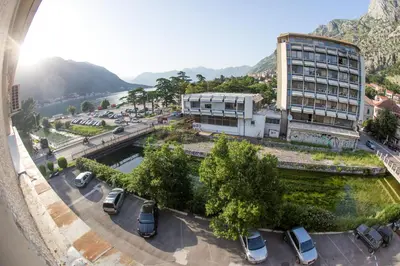 a building with cars parked in a parking lot at Apartman Kotor in Kotor