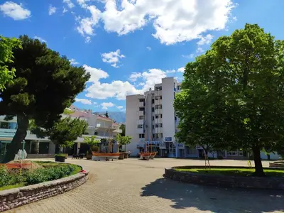 a park with trees and benches and a building at Apartman La Siesta in Bar