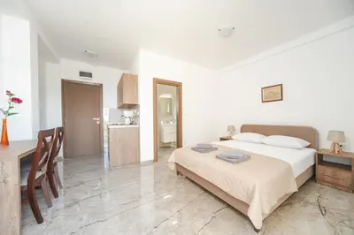a bedroom with a bed and a table and a kitchen at Apartmani Agape in Petrovac na Moru