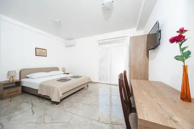 a bedroom with a bed and a table with a vase of flowers at Apartmani Agape in Petrovac na Moru