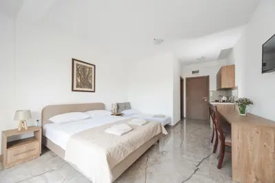 a bedroom with a large bed and a kitchen at Apartmani Agape in Petrovac na Moru