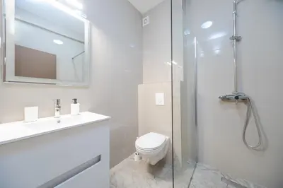 a white bathroom with a toilet and a shower at Apartmani Agape in Petrovac na Moru