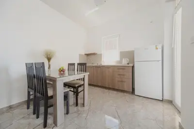 a kitchen with a table and chairs and a refrigerator at Apartmani Agape in Petrovac na Moru