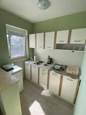 a kitchen with white cabinets and a window at Apartments Klikovac Liman II in Ulcinj