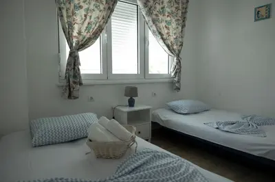 a bedroom with two twin beds and a window at Three Palms Apartments Novakovic in Petrovac na Moru