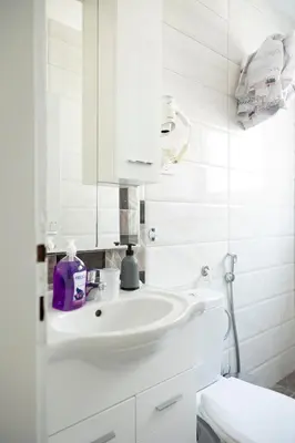 a white bathroom with a sink and a mirror at Three Palms Apartments Novakovic in Petrovac na Moru