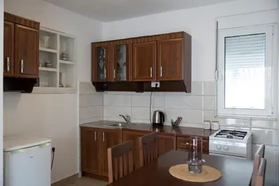 a kitchen with wooden cabinets and a table and a window at Three Palms Apartments Novakovic in Petrovac na Moru