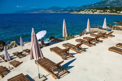 a row of chairs and umbrellas on a beach at Apartments Limunada in Utjeha