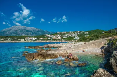 a beach with a group of people in the water at Apartments Limunada in Utjeha