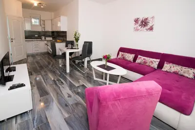a living room with a purple couch and a table at Apartments Limunada in Utjeha