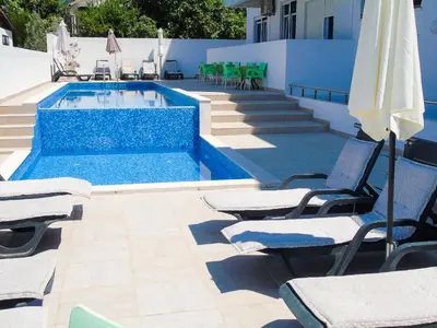 a swimming pool with lounge chairs and an umbrella at Apartments Limunada in Utjeha