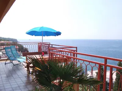 a balcony with a table and a blue umbrella at Monterama Apartments in Sutomore