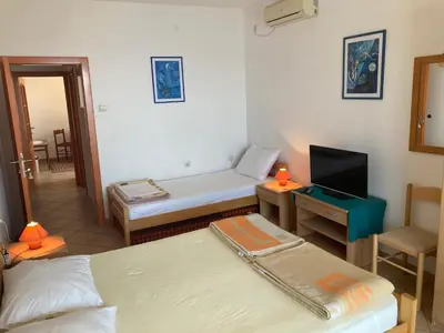 a room with two beds and a desk with a television at Monterama Apartments in Sutomore