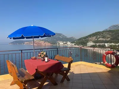 a table with a blue umbrella on a balcony at Monterama Apartments in Sutomore