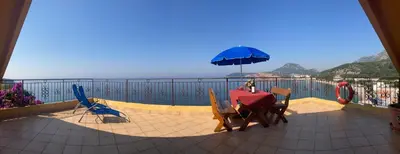 a table and chairs with an umbrella on a balcony at Monterama Apartments in Sutomore
