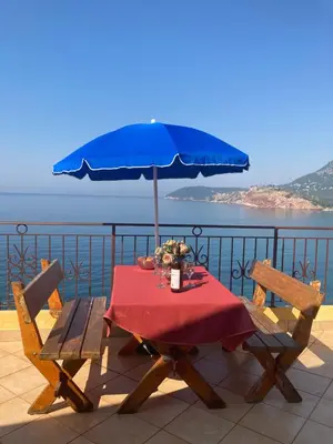a table with a blue umbrella on a balcony at Monterama Apartments in Sutomore