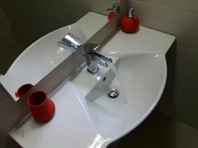a white bathroom sink with red cups on it at Apartment Maja in Budva
