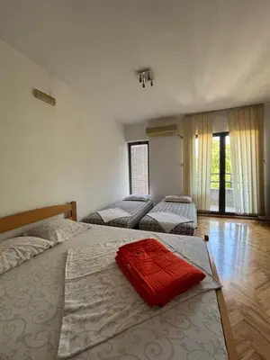 a bedroom with two beds and a large window at Apartment The Royal Pg in Podgorica
