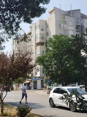 a man walking down a street next to a white car at Alex Apartment in Bar
