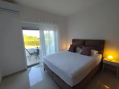 a bedroom with a bed and a balcony with a table at Guest House AGA in Ulcinj
