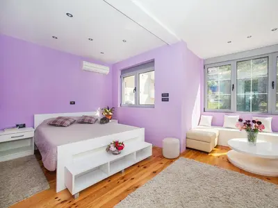 a purple bedroom with a bed and a couch at Apartments Princess View in Sveti Stefan