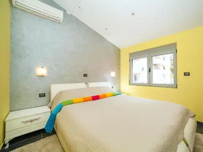 a bedroom with a white bed with a colorful blanket at Apartments Princess View in Sveti Stefan