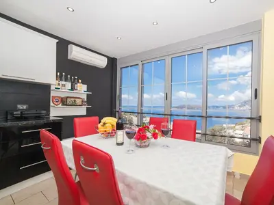 a dining room with a table and red chairs at Apartments Princess View in Sveti Stefan