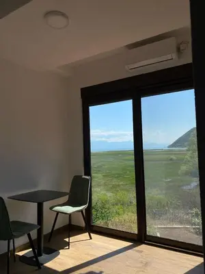 a room with a table and chairs and a large window at Draga`s rooms in Virpazar